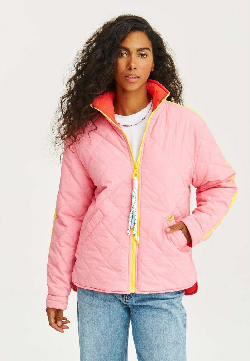 Prošívaná růžová bunda s žlutými akcenty a červenou podšívkou. Má vysoký límec, zip a ozdobné stahovací jezdce.