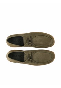 Zapatos de ante verde oliva con puntera redonda, cordones marrones y suela de goma beige. El interior presenta texto de marca en negro.