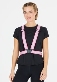 Heijastava turvavaljaat kirkkaan vaaleanpunaisena harmailla raidoilla, jossa on säädettävät hihnat ja keskimmäinen solki, käytetään mustan paidan päällä.