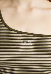 Top de malha às riscas em verde e bege, com gola arredondada e logótipo "Levi's" bordado no peito. Tecido suave e elástico.