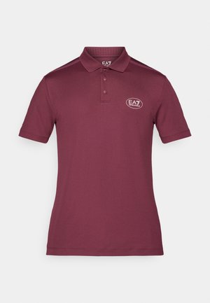 Polo burdeos hecho de tela suave, con cuello, dos botones y un logo circular en el lado izquierdo del pecho. Mangas cortas.