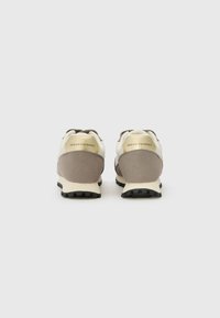 Scarpe da atletica marroni e crema con una parte superiore testurizzata, dotate di una suola ammortizzata e marchiatura sul tallone. La vista posteriore mostra il design con lacci.