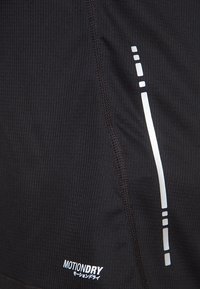 Svart fukttransporterande tyg med ribbad struktur, med vita reflexdetaljer och "MOTIONDRY"-logotypen i det nedre hörnet.