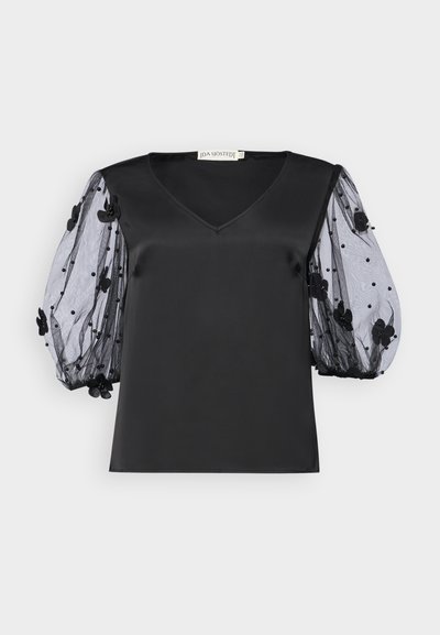 Haut en satin noir avec un décolleté en V, doté de manches bouffantes en tulle noir transparent ornées d'appliqués floraux et de perles.