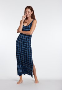Maxime dress in tummansininen with blue circular patterns, featuring a scoop neckline, side slits, and striped accents at the hem. Stretchy fabric.