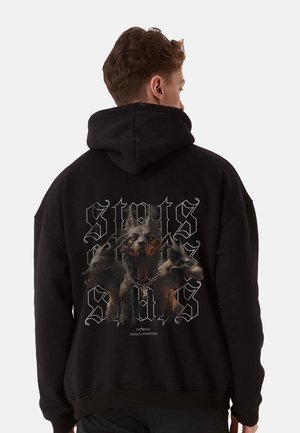 Black hoodie featuring a graphic of three dogs, one in front with a fierce expression. Includes stylized text and a chain design.