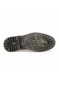 Zool van een versleten zwart leren laars met diepe loopvlakken en witte stiksels, met het merk "Pine Legend".