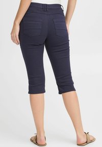Pantaloni capri navy in tessuto elasticizzato, con vita a media altezza, due tasche posteriori e una vestibilità aderente sulle gambe, che terminano a metà polpaccio.
