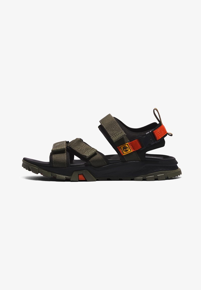 Sandale de sport outdoor avec des sangles ajustables vert olive, une semelle noire, des accents orange et une étiquette de marque sur le côté.