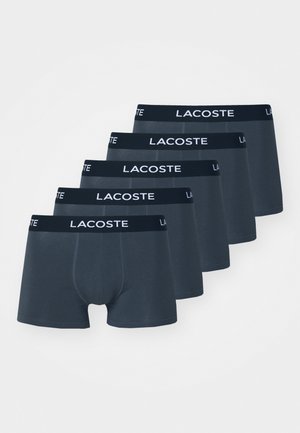 Dunkelblaue Baumwollshorts mit einem schwarzen Bündchen, das mit weißem "LACOSTE"-Branding versehen ist, fünf Stück in einer Reihe angeordnet. Glatte Textur.