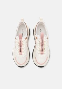 Vita idrottsskor med rosa accenter, texturerat mesh och syntetmaterial, gummisula och snören med tryckt logotyp. Har en dragflik.