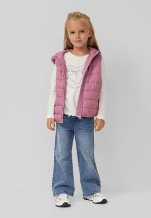 Roze gewatteerd vest met een capuchon, gedragen over een witte langslavenshirt met een paarse paardenafbeelding, gecombineerd met lichtblauwe wijde jeans.
