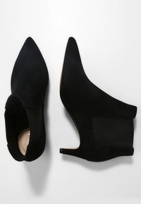 Svarta mocka ankelstövlar med spetsig tå, låg klack och elastiska sidopaneler. Slät textur med en ren design.