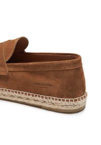 Zapato marrón de ante sin cordones con una textura suave, que presenta una suela de cuerda trenzada y una etiqueta de marca grabada en el costado.