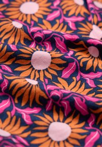 Stof din bumbac cu un model floral, având mari floarea-soarelui portocalii și frunze roz pe un fundal albastru închis. Textură moale, culori vibrante.