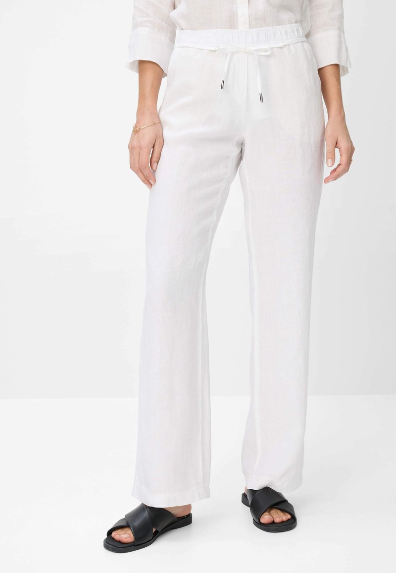 Witte linnen broek met een relaxte pasvorm, elastische tailleband en trekkoord. Gecombineerd met zwarte sandalen met een kruisband ontwerp.