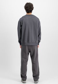 Grå sweatshirt med rund hals och ribbade ärmslut, matchad med grå mjukisbyxor. Tillverkad av bomull, avslappnad passform, enkel design.