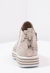 Stivale con motivo di pelle di serpente in una combinazione di colori beige e marrone, dotato di una cerniera laterale e di una suola platform a strisce bianche e marroni.