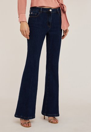 Donkerblauwe flared jeans met een gladde denimtextuur. Kenmerken zijn onder andere voor- en achterzakken, riemlussen en een subtiele glans.