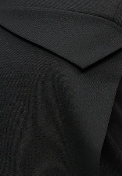 Κοντινό πλάνο μαύρου υφάσματος με διπλωμένη φάσα, που αποκαλύπτει λεπτή υφή και ομαλό, δομημένο υλικό.