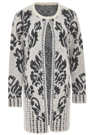 Witte en zwarte geblokte lange cardigan met een fuzzy textuur, open voorkant en decoratieve studs op de manchetten. Beschikt over een ingewikkeld bloemontwerp.