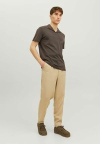 Polo a maniche corte grigio scuro, pantaloni in lino beige, scarpe marroni. Design semplice, vestibilità rilassata, tessuto morbido, senza motivi o accenti.