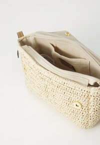 Borsa in paglia intrecciata color crema con esterno texturizzato, dotata di fodera in tessuto beige, due tasche interne e dettagli metallici dorati.