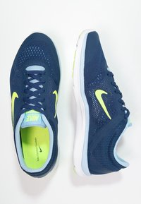 Scarpe da ginnastica blu navy con superiore in mesh traspirante, dettagli giallo neon e suola bianca. Presentano lacci e una linguetta imbottita.