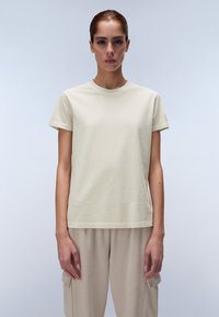 T-shirt in cotone beige chiaro con maniche corte e scollatura rotonda, caratterizzato da un colore uniforme e una vestibilità casual. Visualizzato frontalmente.