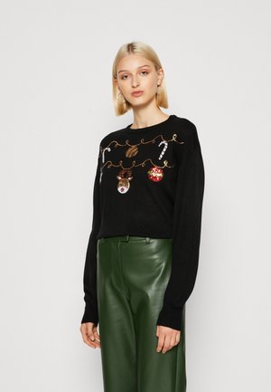 Black sweater with long sleeves featuring embroidered festive decorations, including ornaments and candy canes, paired with green leather pants.