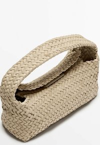 Beżowa pleciona torebka o zaokrąglonym kształcie i górnym uchwycie. Tekstura jest gładka, z plecionym wzorem, z delikatnym zapięciem na klapkę.