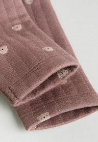 Blødt, ribbet mauve stof med små, lyse bjørnemotiver. Har en foldet manchet med pæn syning og en glat tekstur.