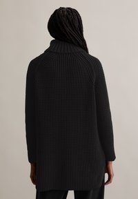 Schwarzer Strickcardigan mit hohem Kragen, Waffelstruktur und langen Ärmeln. Das Design zeichnet sich durch eine lockere Passform und einen gespaltenen Saum aus.