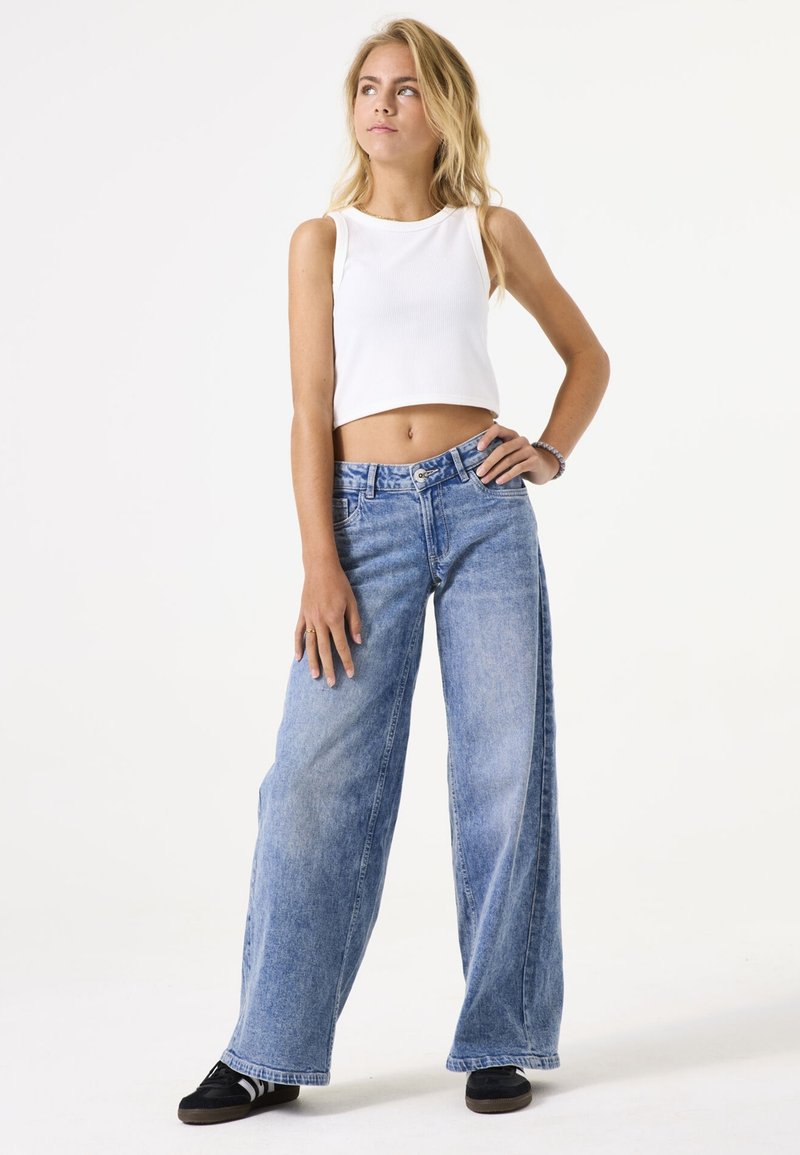 Lichte blauwe denim jeans met wijde pijpen en een hoge taille, gecombineerd met een witte geribbelde crop top, met een subtiele textuur en een losse pasvorm.