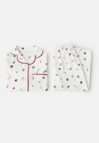 Bela bombažna pižama s rdečimi obrobami, ki vsebuje vzorec ingverjevih piškotov, bonbonov, daril in holly, razporejena na beli podlagi.