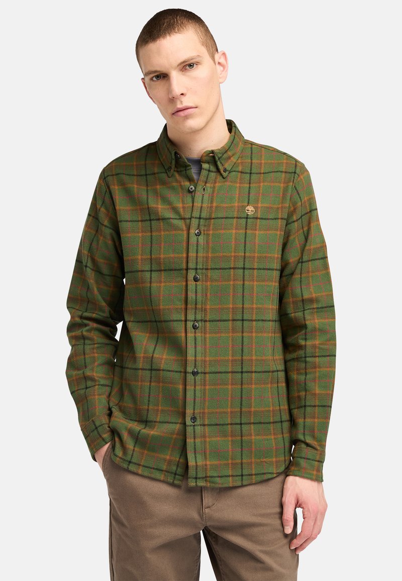 Groene geruite flanellen shirt met bruin en oranje accenten, voorzien van een button-down kraag en een klein logo op de borst.