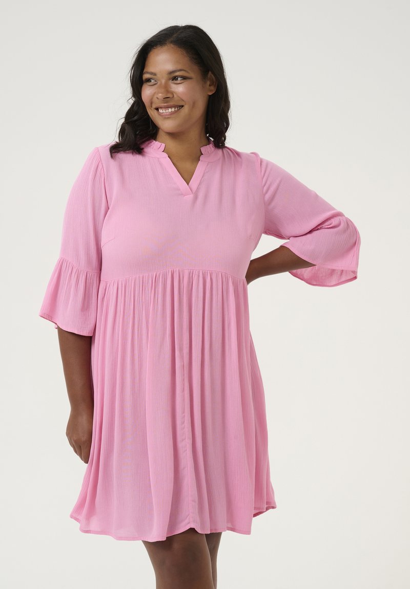 Robe rose, longueur genou, avec un décolleté en V et des manches 3/4 évasées. Tissu texturé, taille froncée et jupe ample.