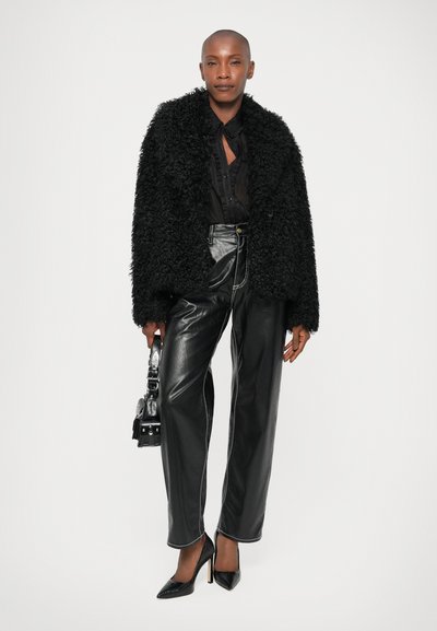 Μαύρο ψεύτικο γούνινο μπουφάν, διάφανο μαύρο πουκάμισο με κουμπιά, ψηλόμεσα μαύρα δερμάτινα παντελόνια με άσπρες ραφές και μαύρες στιλέτο γόβες.