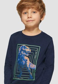 Marineblauwe T-shirt met lange mouwen, voorzien van een kleurraf dinosaurustekening en geometrische patronen in groen en blauw op de voorkant. Van katoen.