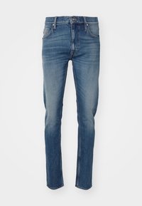 Jeans de mezclilla de corte ajustado en lavado azul claro a medio con sutil desgaste, diseño de cinco bolsillos y corte recto en la pierna. Cierre estándar con cremallera.