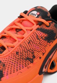 Sapatilhas Nike Air Max em laranja-brilhante e preto, com padrão texturizado, atacadores a condizer e almofada de ar visível na sola.