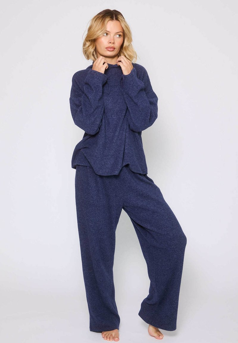 Marineblauw loungeoutfit van zachte stof, bestaande uit een lange mouwtop met een ontspannen pasvorm en bijpassende broek met wijde pijpen.