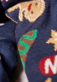 Marineblauer Stoff mit bunten Strickmustern von Lebkuchenmännern, Zuckerstangen und einem roten Netflix-Logo. Weiche Textur und detaillierte Designs.