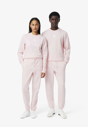 Sudaderas y pantalones de chándal a juego en color rosa, hechos de una tela suave, con un logo blanco en el pecho. Ajuste cómodo con puños y cintura elásticos.