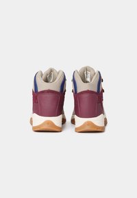 Paire de bottes de randonnée bordeaux et beige avec des accents bleus, vues de dos, sur un fond gris clair uni.