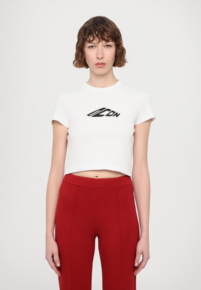 T-shirt blanc court à manches courtes, avec un logo graphique noir sur la poitrine. Associé avec un pantalon rouge taille haute.