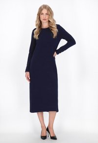 Navy blue pitkähihaine midi-mekko suoran siluetin ja nappikoristeiden kanssa ranteessa, valmistettu pehmeästä neulemateriaalista.