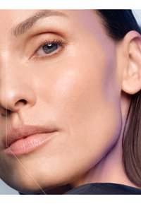  Närbild av ett ansikte med slät, klar hud. Kännetecknen inkluderar definierade kindben, fylliga läppar och subtil ögonmakeup. Håret är bakåtdraget.