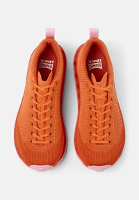 Bright orange sneakers with a mesh upper, featuring pink accents and laces. The soles are semi-transparent and rounded at the front.