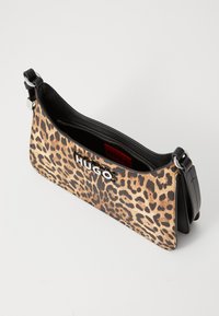 Borsa a tracolla in stampa leopardata con una cinghia in pelle nera, chiusura con zip e logo "HUGO" in bianco sul davanti. Superficie testurizzata e silhouette elegante.